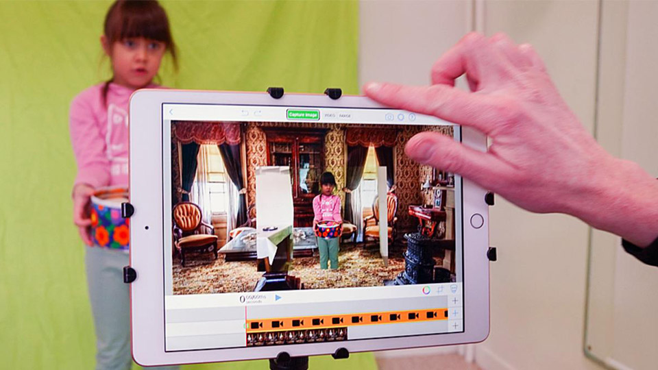 en läsplatta i förgrunden visar barnet i en spännande miljö medan samma barn står bakom läsplattan med en "green screen" bakom sig.