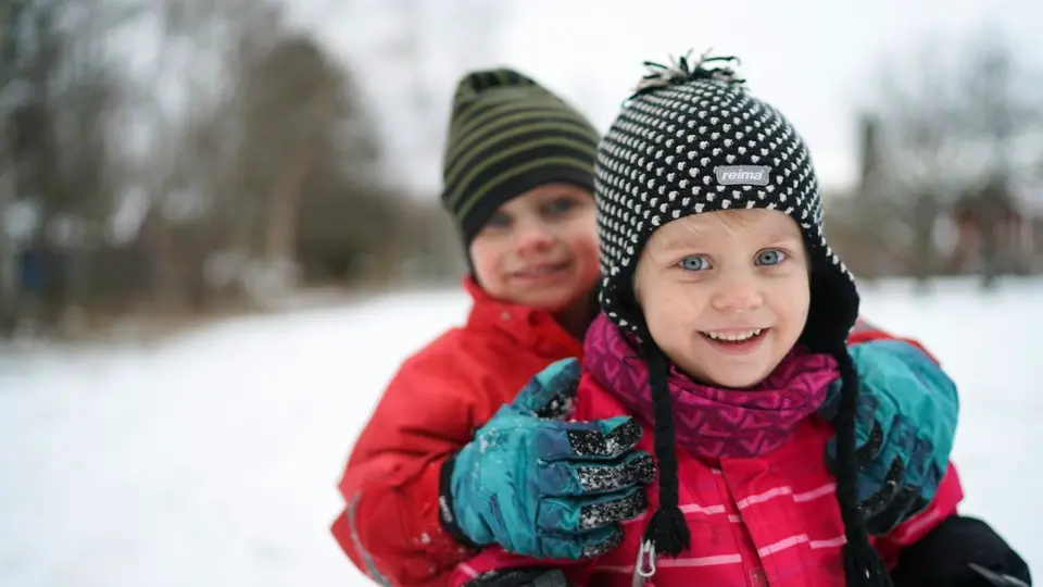 Två vinterklädda barn leker i snön