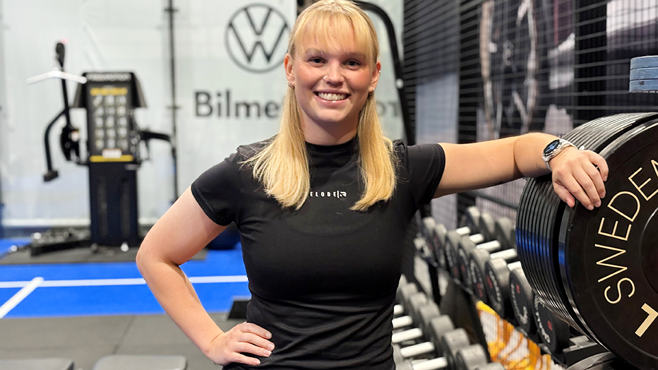 Kvinna ler i gymmiljö.