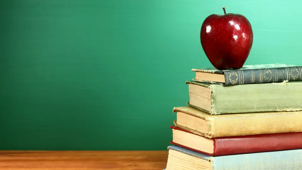 Genrebild för skola och utbildning. Staplade böcker med ett äpple på.