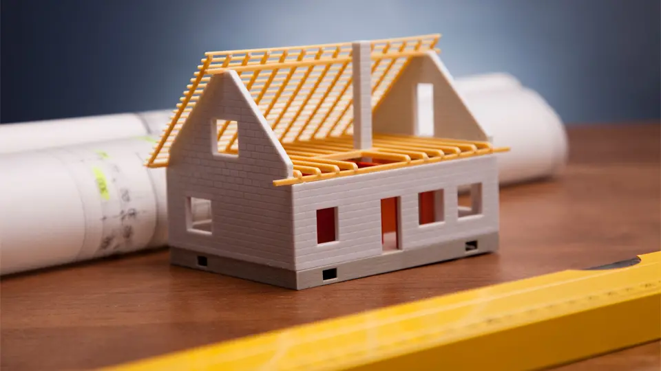 Modell av ett vitt hus, ritning och gult vattenpass 