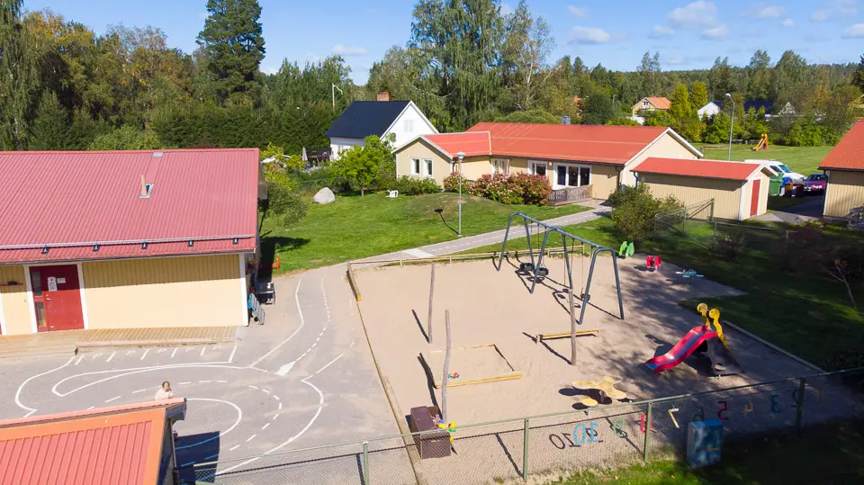 Stråtjära förskolas utomhuslekplats med gungor och sandlåda.
