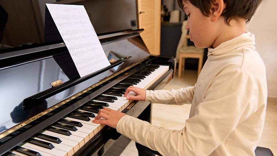 Ett barn fokuserar på att spela piano.